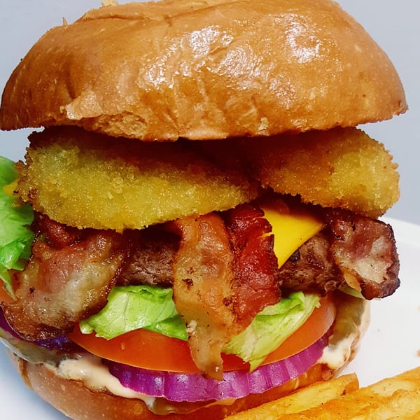 A Springdale Cafe burger with bacon, cheese, onion rings, lettuce, tomato, and red onion.